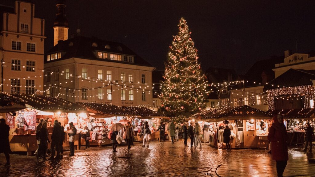 Gezellige kerstmarkt met verlichte kraampjes en grote kerstboom op een sfeervol stadsplein