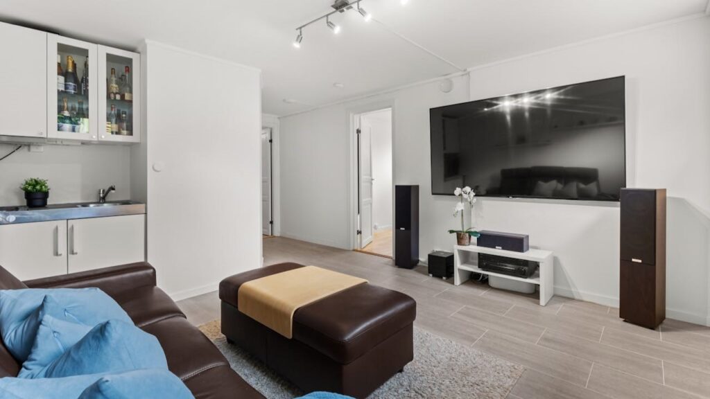 Grootbeeld-tv gemonteerd aan de muur in een strakke, moderne woonkamer met surround sound