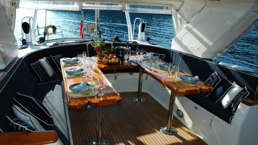 Gedekte buitentafel met uitzicht op zee aan boord van een van de grootste jachten ter wereld, omgeven door kussens en glaswerk