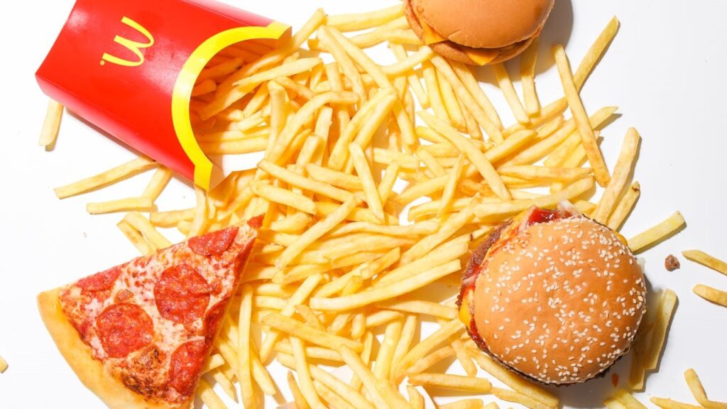 Fastfoodketens zoals McDonald’s tonen iconisch fastfood met friet, hamburger en pizza op een witte achtergrond.