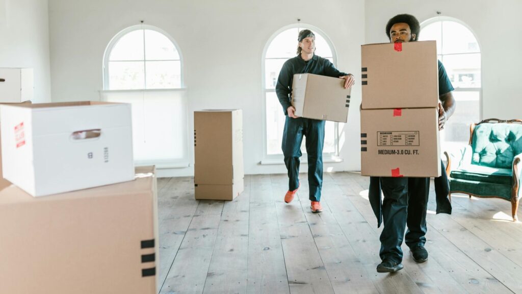 Mannen dragen verhuisdozen in lichte kamer met houten vloer tijdens verhuizing ter voorkoming van verhuisfouten