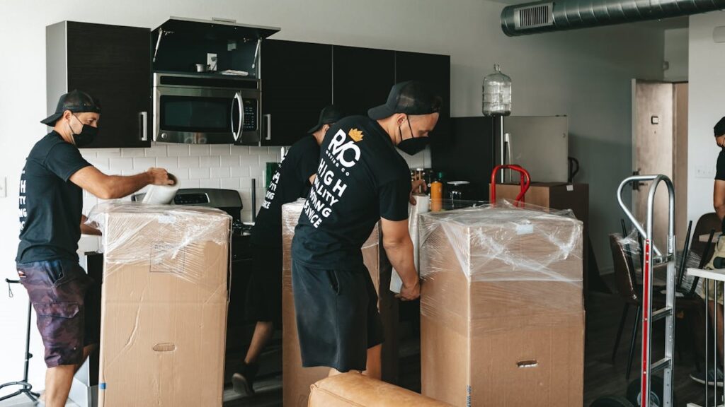 Verhuisteam pakt grote dozen in en beschermt meubels tijdens verhuizing in moderne keuken ter voorkoming van verhuisfouten