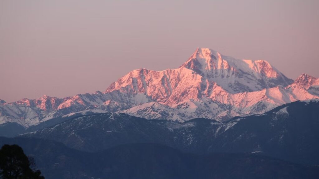 Sneeuwbedekte bergtop in de Himalaya baadt in roze zonlicht tijdens zonsopgang