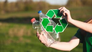Twee plastic flessen en een recyclelogo worden vastgehouden in een groene buitenomgeving