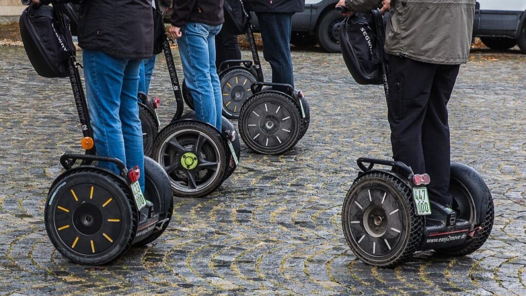 Groep mensen op Segways tijdens een rondrit op een natte, stenen ondergrond – productflops in mobiliteit

