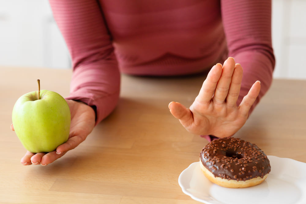 vrouw kiest voor appel met dieet in plaats van donut